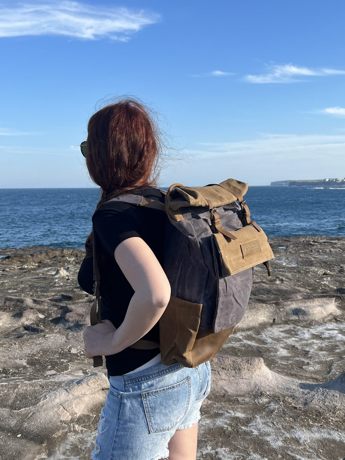 Side view of the leather and waxed canvas backpack on the coast